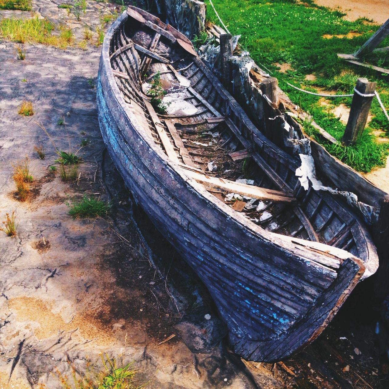 field, high angle view, transportation, grass, outdoors, day, no people, wood - material, nature, metal, abandoned, mode of transport, landscape, old, wheel, rusty, sunlight, tranquility, close-up, green color