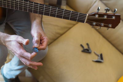 Midsection of man preparing guitar in home