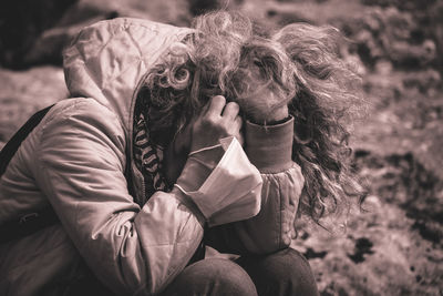 Midsection of man holding woman sitting outdoors