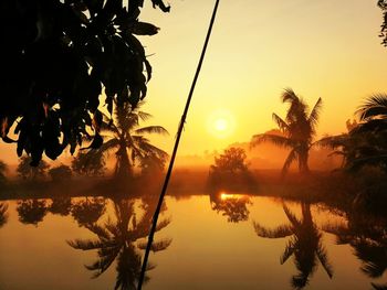 Silhouette trees by lake against sky during sunset