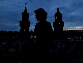 Silhouette people sitting in temple against sky in city