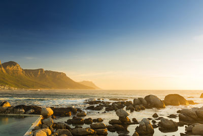 Rocks on beach against sky during sunset