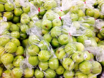 Full frame shot of granny smith apples packed in plastic at market for sale