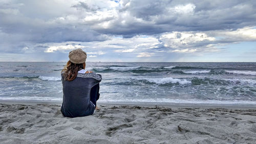 Rear view of woman sitting on shore at beach