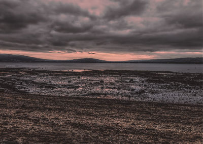 Scenic view of sea against dramatic sky during sunset