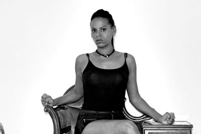 Portrait of young woman sitting against white background