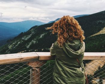 Woman with umbrella on mountain against sky