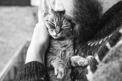 Midsection of man holding cat sitting outdoors