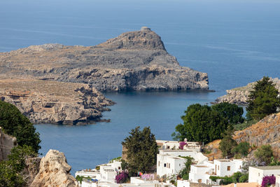 View at a bay in lindos with white houses in the foreground, rocky coastline of the aegean sea