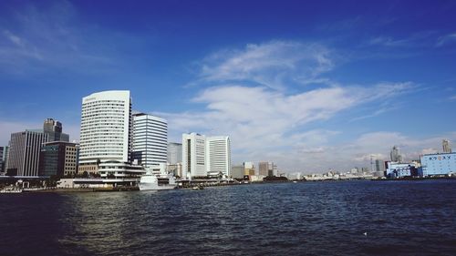 Sea by buildings against sky in city
