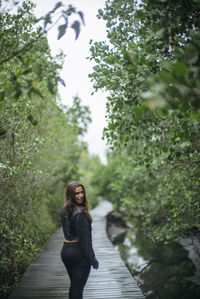 Woman standing on footpath amidst plants