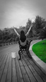 Rear view of woman sitting in park against sky