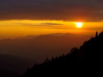 Scenic view of silhouette mountains against orange sky