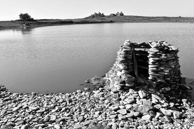 Stack of stones in lake against sky