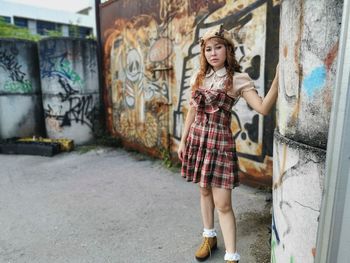 Full length portrait of woman standing against graffiti wall