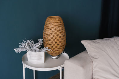 Wicker lamp on the coffee table near the white sofa in the modern living room of the house