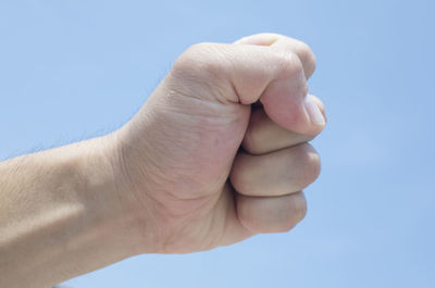 Close-up of person hand against blue sky