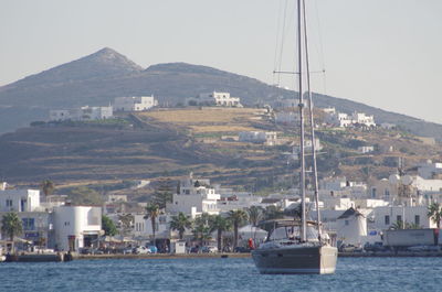 Boats in sea by mountains against clear sky