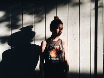 PORTRAIT OF YOUNG WOMAN STANDING ON WALL