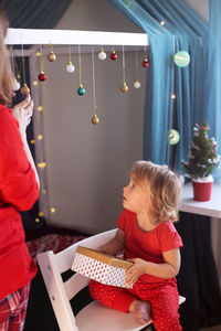 High angle view of girl holding gift box sitting at home