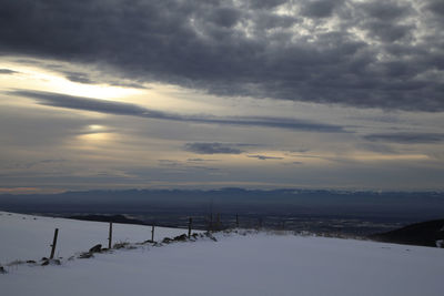 Scenic view of snow covered field against sky during sunset