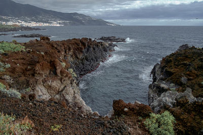 Scenic view of sea by cliff against sky