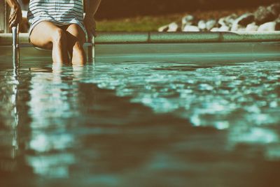 Midsection of woman in swimming pool on sunny day