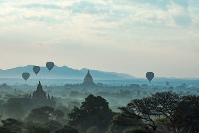 Silhouette hot air balloons over historic temple against sky