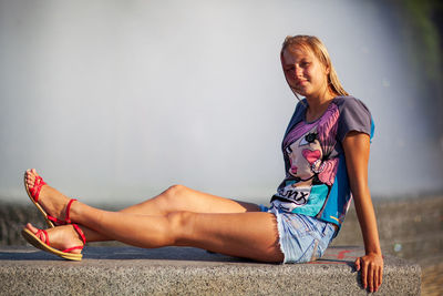 Midsection of woman sitting against wall