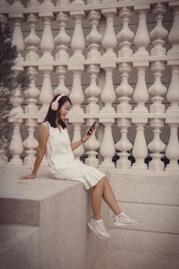 Full length of young woman standing against wall