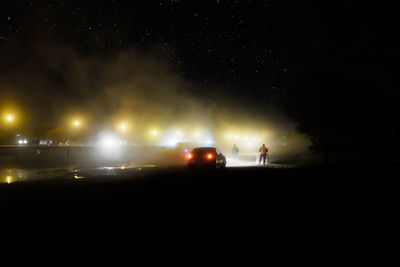 Cars on illuminated street at night