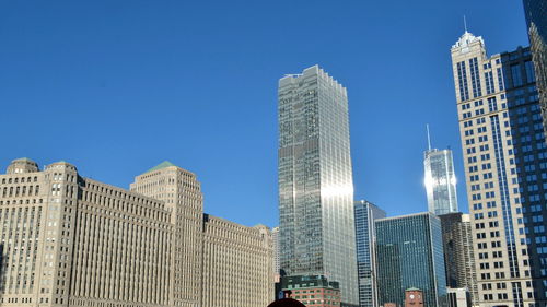 Low angle view of skyscrapers against blue sky