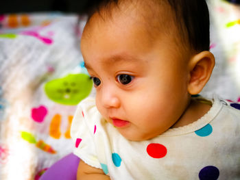 Portrait of cute baby girl lying on bed at home