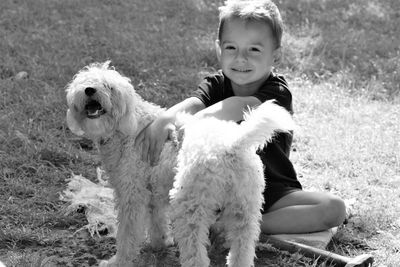 Portrait of smiling boy with dog sitting outdoors