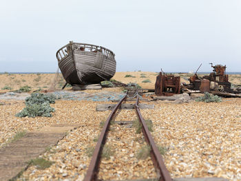 Abandoned railroad tracks on field against sky