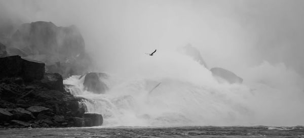 Scenic view of sea waves splashing on rocks against sky