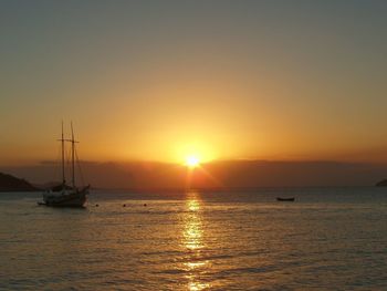 Boat sailing in sea at sunset