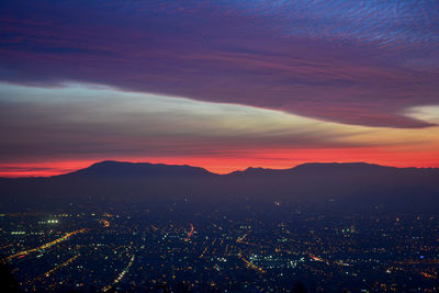 Aerial view of illuminated city against sky at sunset