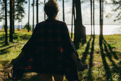 Rear view of woman standing against trees