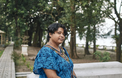 Portrait of a pensive looking indian woman standing near ledge of a garden-house, near ganges