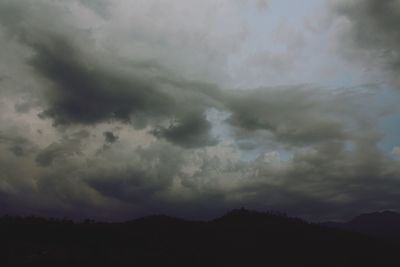 Silhouette of mountain range against cloudy sky