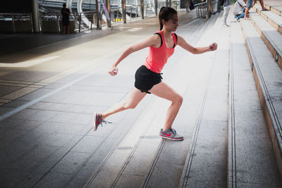 Full length of woman running on footpath in city