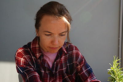 Portrait of young woman looking away against wall