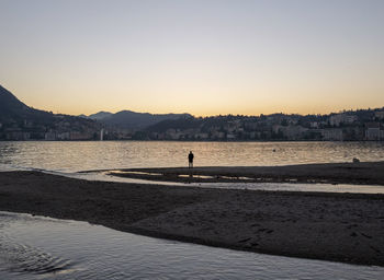 Silhouette person on beach against clear sky during sunset