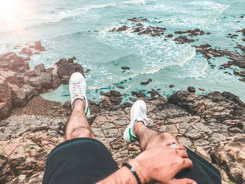 Low section of person on rock by sea