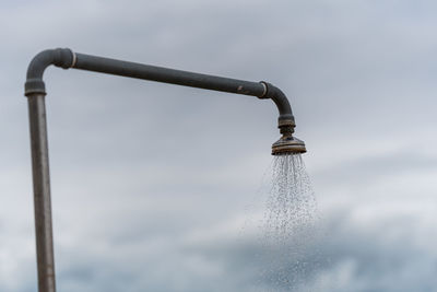 Close-up of water drops on pole against sky