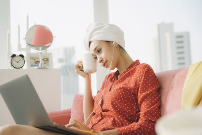 Young woman using phone while sitting on table