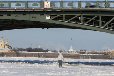 Silhouette of skier riding on ice of the frozen neva river under palace bridge in winter at sunset