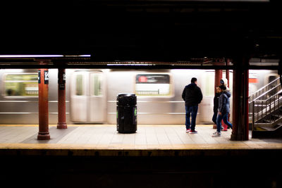 Rear view of people walking on railroad station platform