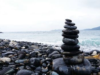 Stack of pebbles on beach against sky